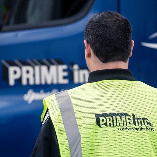 Prime driver looking at his truck with a Prime vest on
