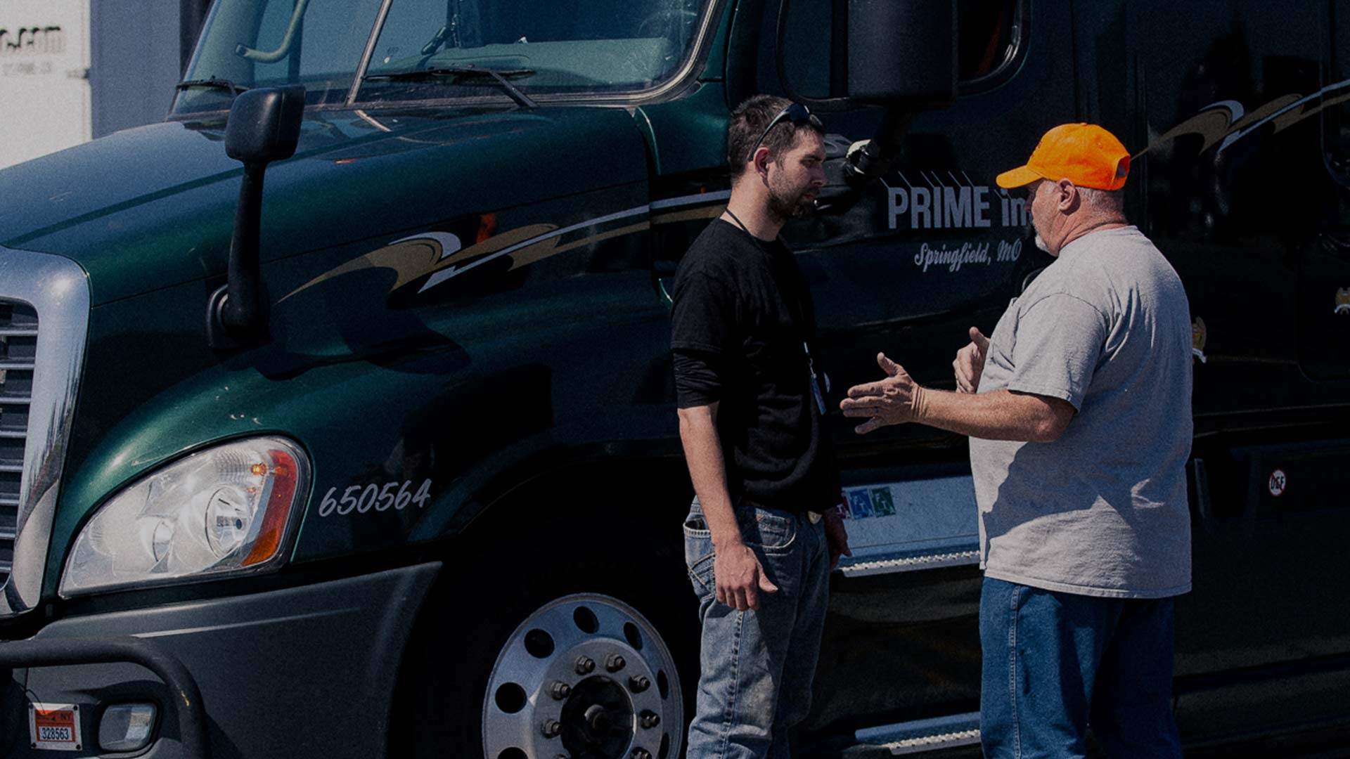 wide shot of experienced driver giving truck driver training to younger driver